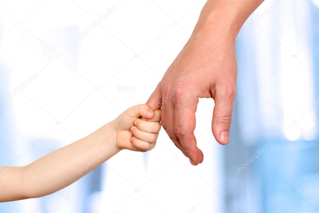 a father  holds the hand of a small child on a blue background