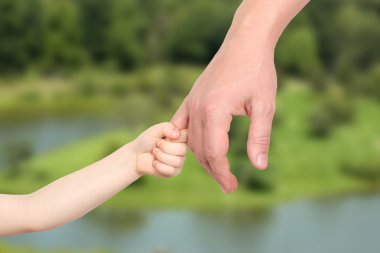 bir baba küçük bir çocuk el yeşil bir arka plan üzerinde tutar.