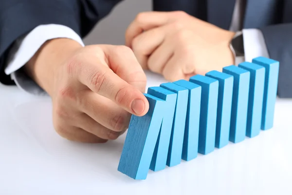 Planning, risk and strategy in business, businessman  holding   wooden blocks.  Businessman Stopping The Effect Of Domino — Stock Photo, Image