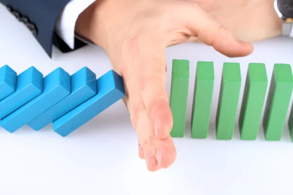 Close-up Of Businessman Stopping The Effect Of Domino With Hand At Desk — Stock Photo, Image