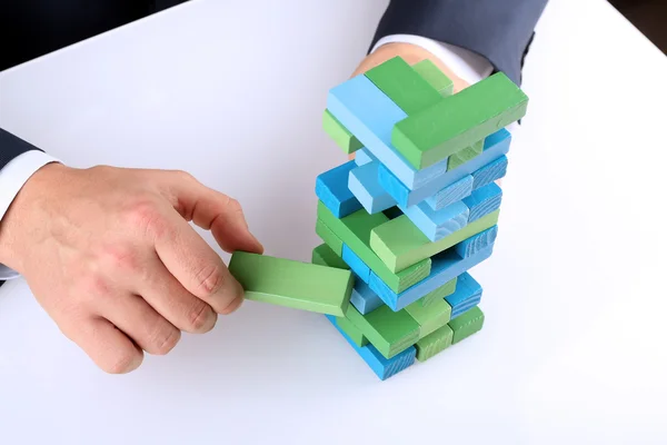 Planning, risk and strategy in business, businessman getting out a wooden block from a tower — Stock Photo, Image