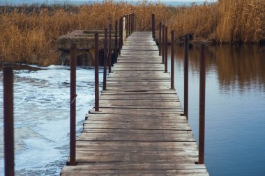 Sakin bir nehir boyunca küçük tahta bir köprü. Barajın içinden geçerek, bakir bir taş ustası gibi. Gölü geçiyoruz. Sonbahar öğleden sonraları ıslak, ahşap duvarcılık.