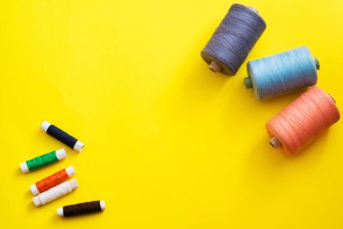 Reels with threads of different colors and sizes on a bright, colorful background. Flat lay. Place for text, copyspace