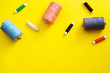 Reels with threads of different colors and sizes on a bright, colorful background. Flat lay. Place for text, copyspace