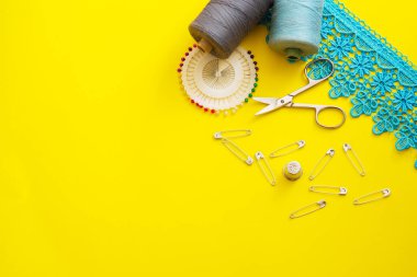 Multi-colored reels with sewing threads, meter tape, scissors on a bright background. Flat lay