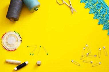 Multi-colored reels with sewing threads, meter tape, scissors on a bright background. Flat lay