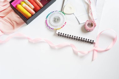 Kesmek ve dikmek için aletler. Terzi çantası. Çok renkli makaralar, şeritler, beyaz arka planda iğneler. Çerçeve, metin için boşluk