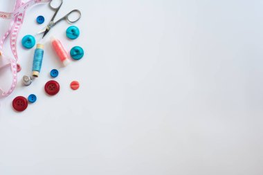 Yerleşim planı. Dikiş malzemeleri - düğmeler, iğneler, farklı renklerde iplikler, beyaz arka planda. Çerçeve, metin için boşluk