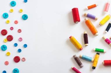 Çerçeve. Farklı renk ve boyutlarda makaralar ve beyaz arkaplanda çok renkli düğmeler. Düz yatıyordu. Metin için yer