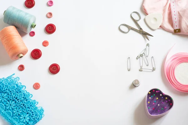 Tools for cutting and sewing. Seamstress kit. Multi-colored reels of threads, tape, needles on a white background. Frame, space for text