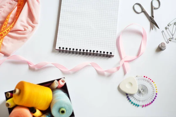 Tools for cutting and sewing. Seamstress kit. Multi-colored reels of threads, tape, needles on a white background. Frame, space for text