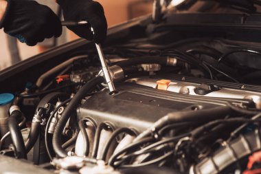 Oto tamircisi araba tamir eder. Çalışan makinenin bakımını yapar..