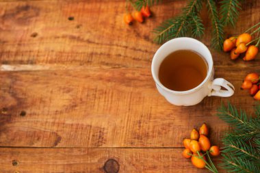 Kış, sıcak atmosfer. Bir fincan sıcak siyah çay, kırmızı eşarp, gül böğürtleni ve ahşap arka planda kış sıcacık bir akşam. Düz konum, yerleşim, metin, kartpostal, yüksek çözünürlük