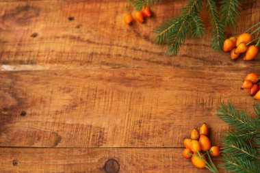 Kış, sıcak atmosfer. Kırmızı eşarplı çerçeve, gül böğürtleni ve ahşap arka planda ladin. Kış akşamı. Düz konum, yerleşim, metin, kartpostal, yüksek çözünürlük