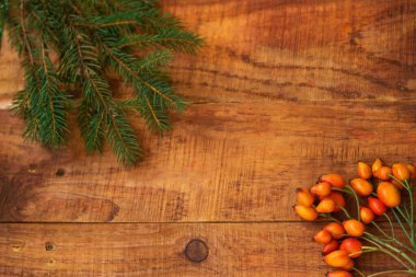 Kış, sıcak atmosfer. Kırmızı eşarplı çerçeve, gül böğürtleni ve ahşap arka planda ladin. Kış akşamı. Düz konum, yerleşim, metin, kartpostal, yüksek çözünürlük