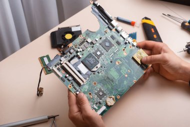 Sihirbaz dizüstü bilgisayarı restore eder. Dizüstü bilgisayarın yedek parçalarına ayrılması. Tahta, iyileşme için dizüstü bilgisayarın bir parçası. Aletleri kullanarak bilgisayar ekipmanlarının bakımı. İçerideki dizüstü bilgisayara bak