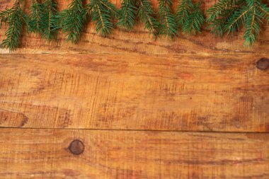 Kış, sıcak atmosfer. Ahşap arka planda ladin dalları olan bir kompozisyon. Yeni yıl geçmişi. Düz konum, metin yeri, kartpostal, çerçeve