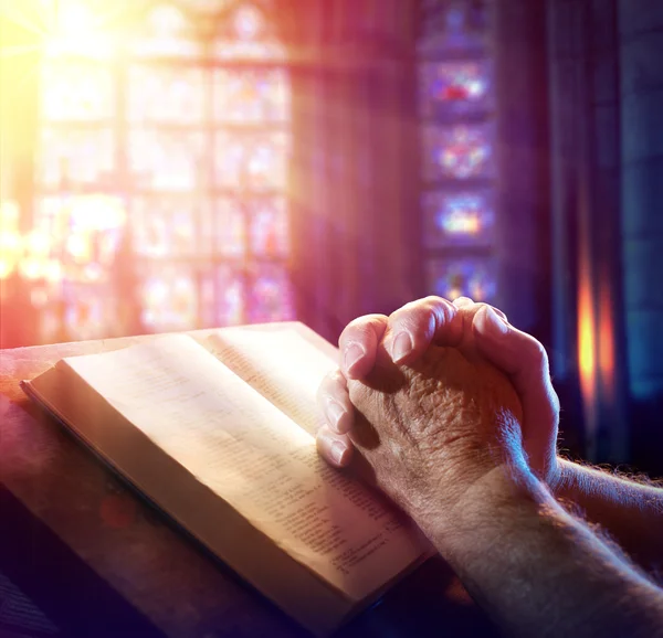 Mãos de um homem orando com a Bíblia — Fotografia de Stock