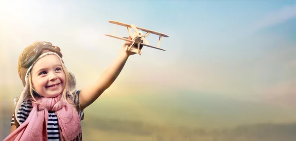 Freiheit zu träumen - fröhliches Kind, das mit Flugzeug gegen den Himmel spielt — Stockfoto