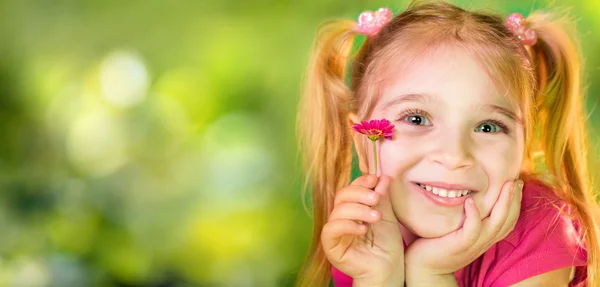 Roztomilé dítě s fialovým Daisy v jarní zahradě — Stock fotografie