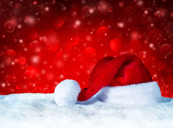 Santa Claus hat with snow and red snowfall background — Stock Photo, Image