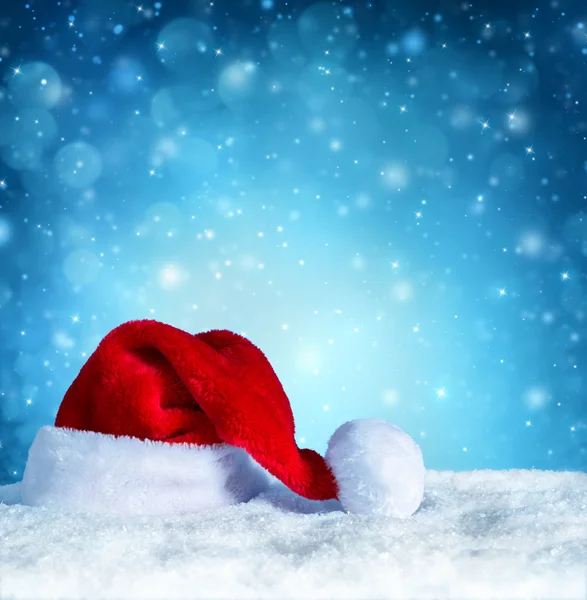 Sombrero de Santa Claus con nieve y fondo azul nevado — Foto de Stock