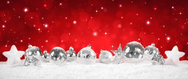 Stříbrné ozdoby na sněhu s červenou jiskra pozadí — Stock fotografie