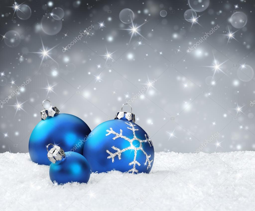 Blue baubles on snow with silver sparkle background