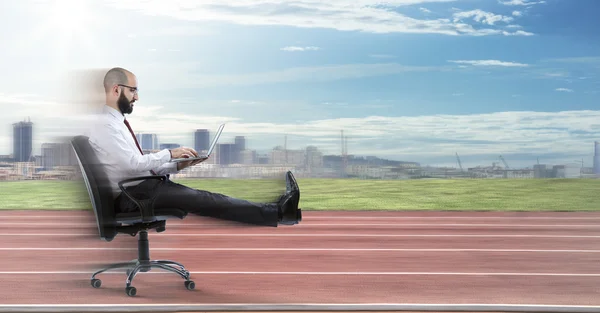 Fast business - businessman sitting with laptop runs on track — Stock Photo, Image