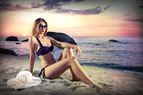 Дівчина в сонцезахисних окулярах лежить на пляжі на заході сонця вінтажний — стокове фото
