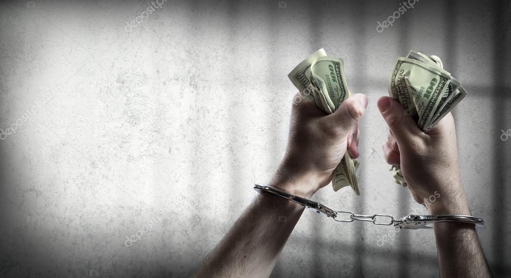 arrest for corruption - man handcuffed holding dollars