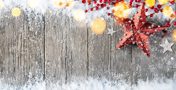 Weihnachtskarte mit Sternenschmuck und Beeren auf schneebedecktem Holz — Stockfoto