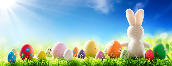 Кролик с украшенными яйцами на солнечном фоне - весна и Пасха
