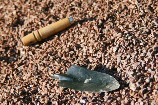        Kırık bir bahçe aleti - bir kürek, çakıllı bir bahçe yolunda yatıyor, sabahın erken saatlerinde yatay olarak güneş ışığında fotoğraflanmış..                        