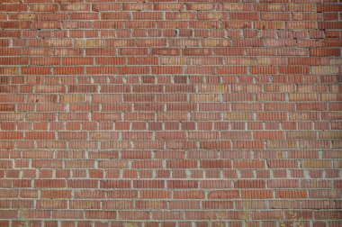 Rough old red brick wall, photographed in low morning sunlight horizontally.