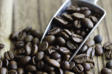Kahve çekirdekleri ve ahşap bir yüzeye bir mutfak kepçesi. Kahve çekirdeklerine odaklanın.