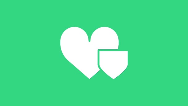 緑の背景にシールドアイコンが隔離されたホワイトハート。愛のシンボル。保険の概念。セキュリティ、安全性、保護、保護の概念。4Kビデオモーショングラフィックアニメーション — ストック動画