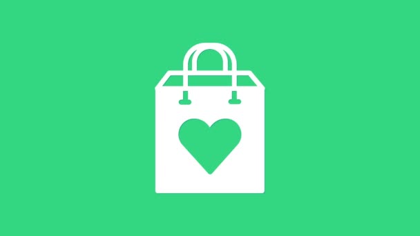 녹색 배경에 하트 아이콘이 있는 흰색 쇼핑백이 있습니다. 가방 가게의 사랑을 하트 아이콘처럼 산다. 발렌틴 데이의 상징이지. 4K 비디오 모션 그래픽 애니메이션 — 비디오