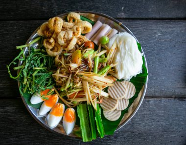 Bir papaya salatası ve yenileyici sebzeler ve kaynamış yumurtalar üstten çekilmiş siyah tabak fotoğrafı. Tayland yerel yemekleri. Sıcak ve baharatlı yemekler..