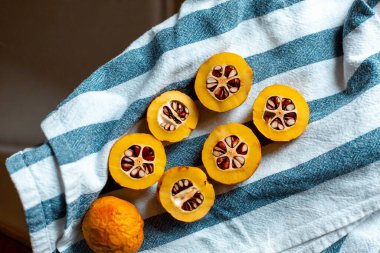 Mavi çizgili havluyla tohumlu turuncu Japon ayvası.