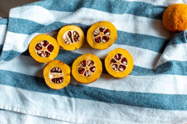 Mavi çizgili havluyla tohumlu turuncu Japon ayvası.