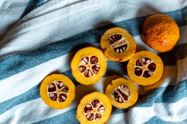 Mavi çizgili havluyla tohumlu turuncu Japon ayvası.