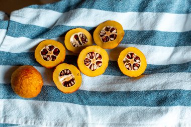 Mavi çizgili havluyla tohumlu turuncu Japon ayvası.