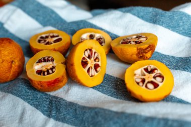 Mavi çizgili havluyla tohumlu turuncu Japon ayvası.