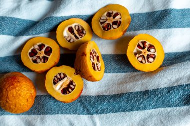 Mavi çizgili havluyla tohumlu turuncu Japon ayvası.