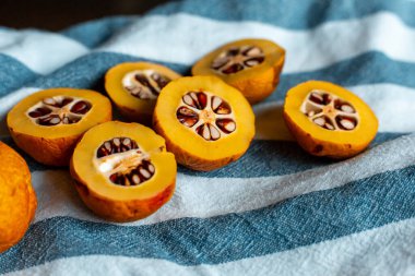 Mavi çizgili havluyla tohumlu turuncu Japon ayvası.