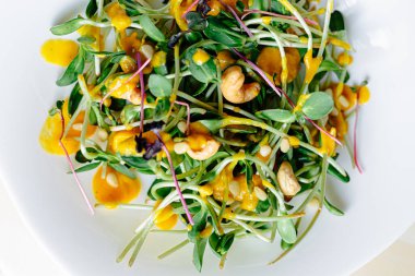 Koyu arkaplan, taze organik salata yaprakları ve beyaz tabakta daireler.