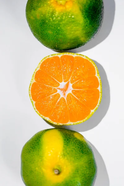 オレンジとライムと熟した緑と黄色のみかんとオレンジのみかんのスライスを白い背景に — ストック写真