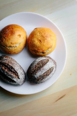 Masanın üzerinde beyaz masa örtüsü olan haşhaş tohumlu çörekler. Asgari stil kavramsal natürmort fotoğrafçılık.