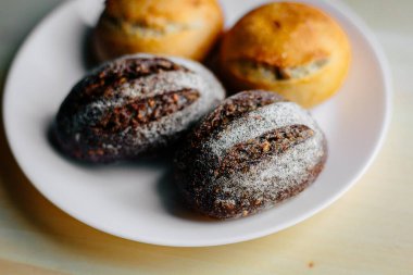 Masanın üzerinde beyaz masa örtüsü olan haşhaş tohumlu çörekler. Asgari stil kavramsal natürmort fotoğrafçılık.